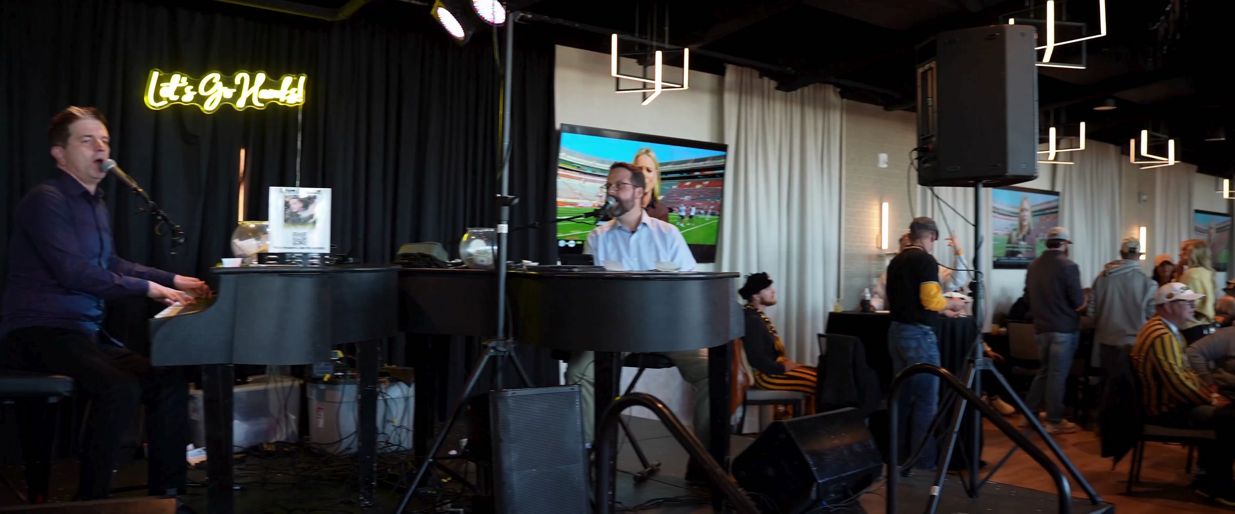 Two Midwest Dueling Pianos performers at facing pianos in an indoor venue.