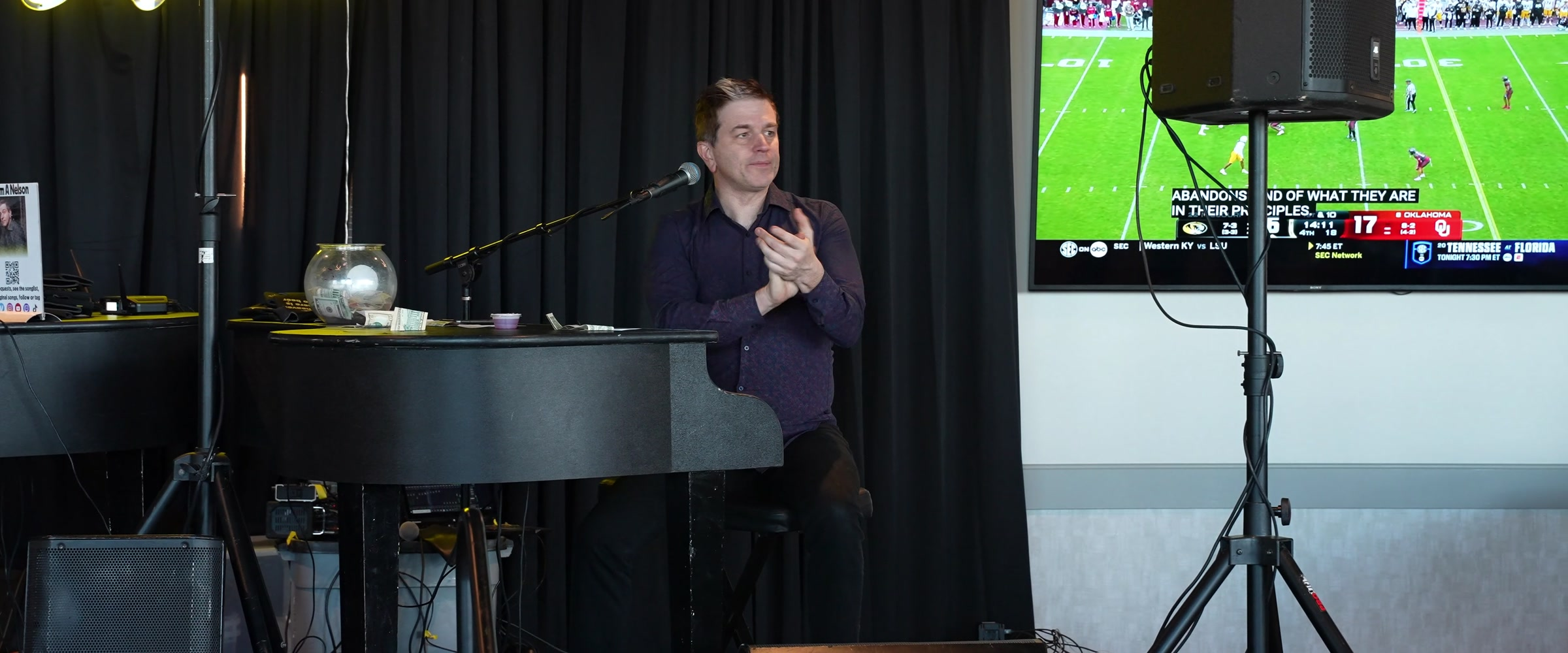 Adam Nelson clapping beside a piano during a Midwest Dueling Pianos show.