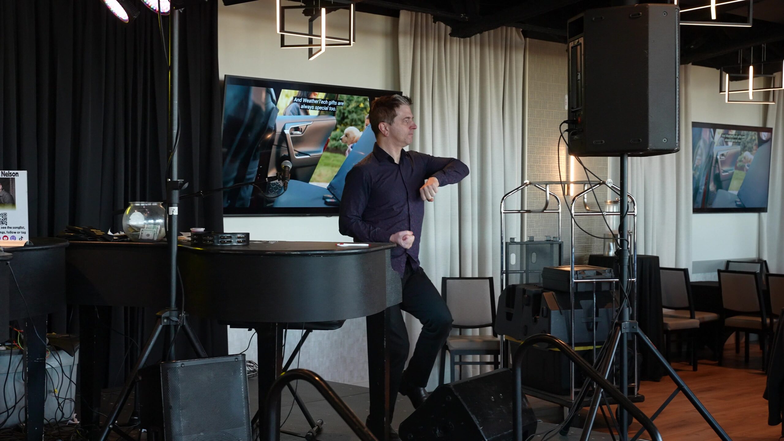 Midwest Dueling Pianos performer gesturing to the audience from beside a black piano.