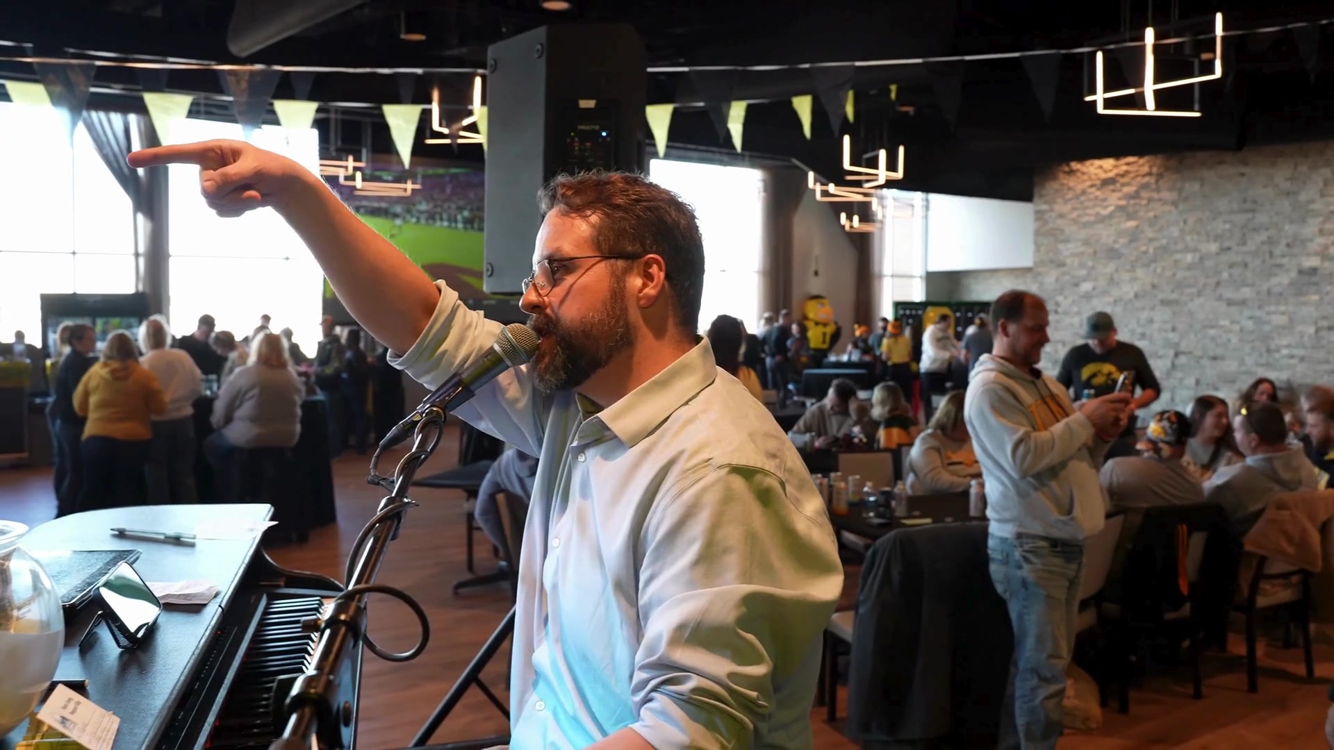 Midwest Dueling Pianos performer pointing toward the audience while singing at a piano.